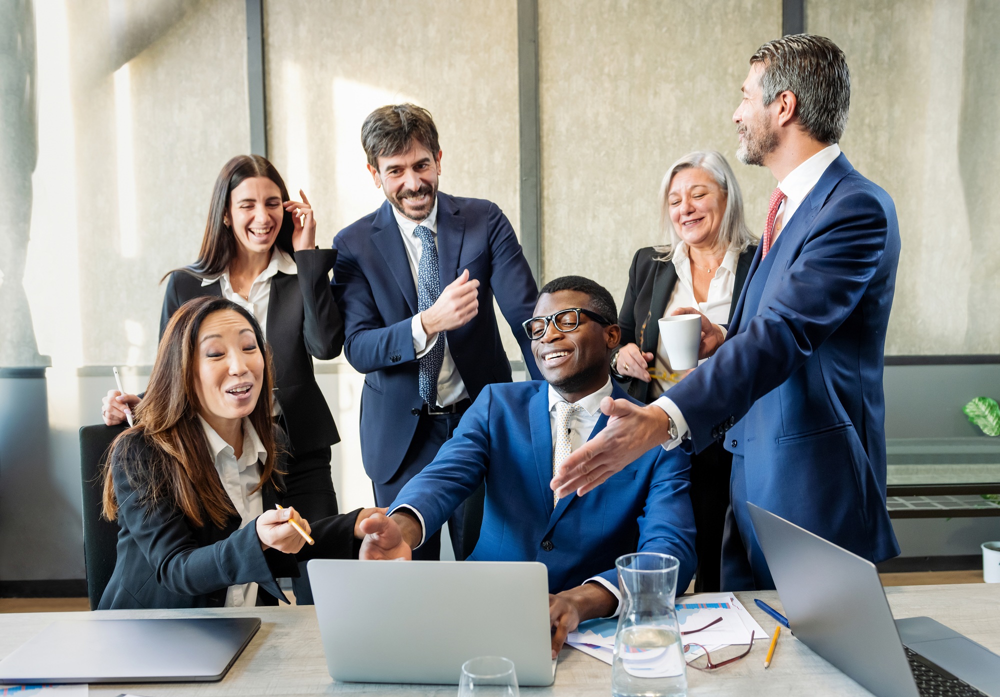 Group of multiethnic businesspeople discussing news near laptop